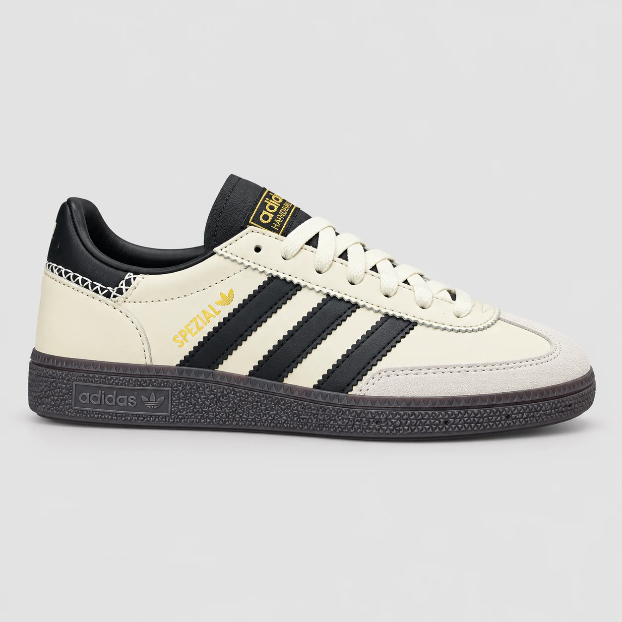 adidas Handball Spezial — Cream / Black / Dark Gum Cream / Black / Dark Gum low-top sneaker with lace-up fastening, layered panels and three-stripe detailing. Browse the cleaned catalogue image and original supplier photo, and select your UK size from 3 to 9.