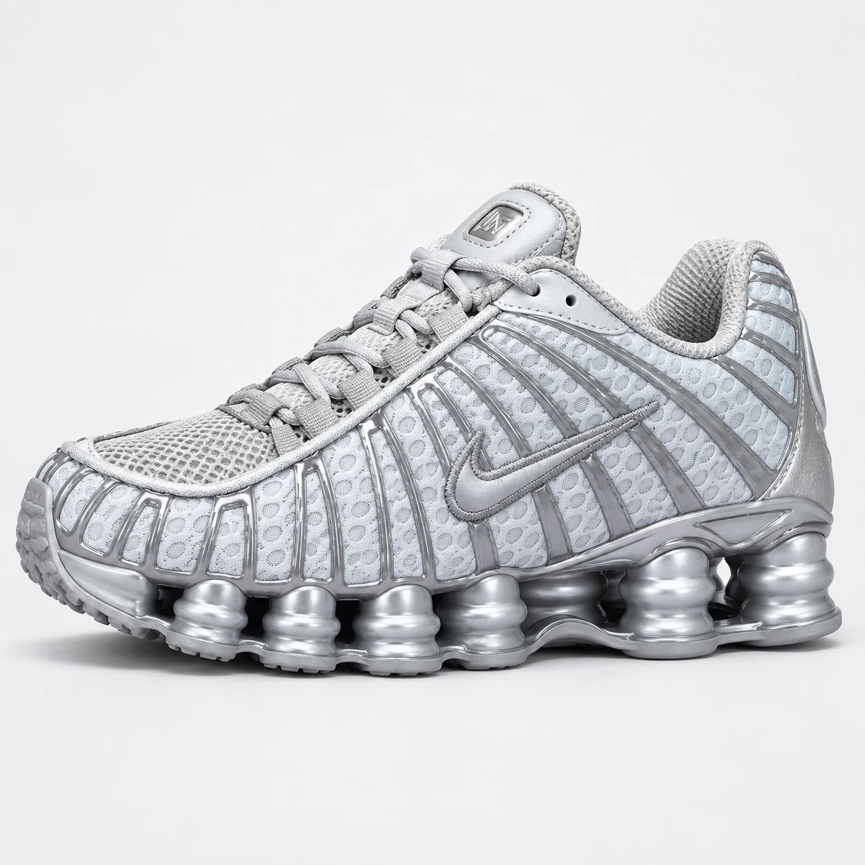 Nike Shox TL — Silver / Grey Silver / Grey low-top sneaker with lace-up fastening, layered panels and visible Swoosh branding. Browse the cleaned catalogue image and original supplier photo, and select your UK size from 3 to 9.